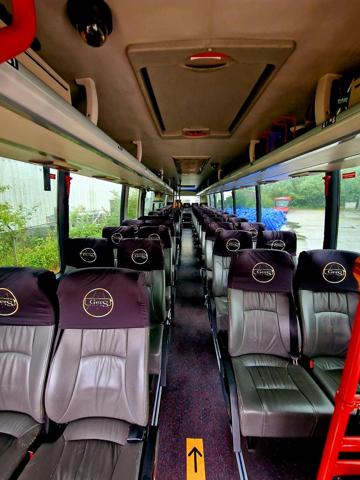 Grijze lederen stoelen met Gers Tours-hoofdsteunhoezen in het interieur van de bus